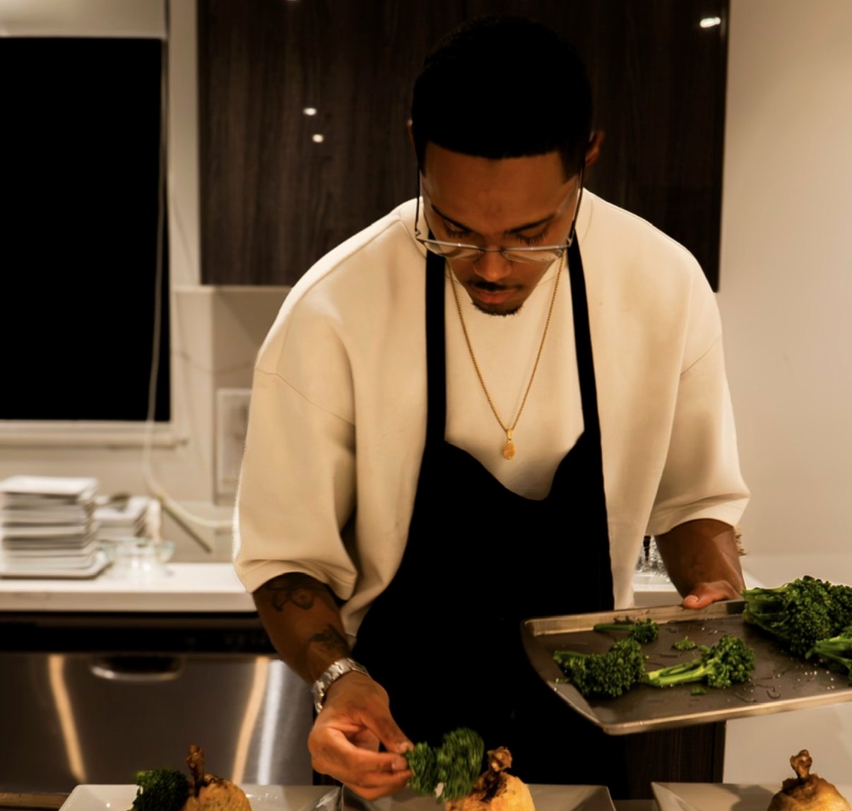 Chef plating a private dinner while guests are served wine at the table